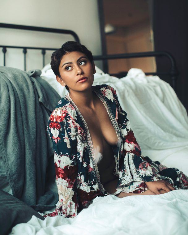 Woman in an open floral robe on a white bed